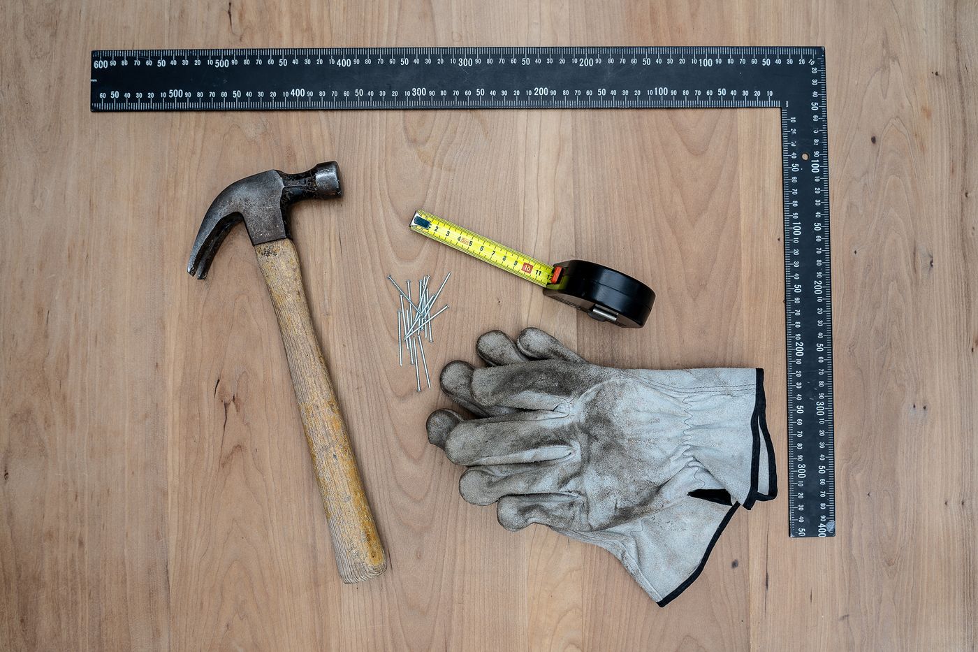Martillo, guantes y escuadra sobre madera
